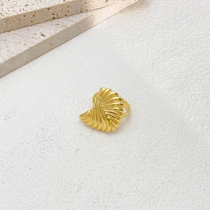 Detailed close-up of golden shell-shaped ring with elegant pleated metal texture