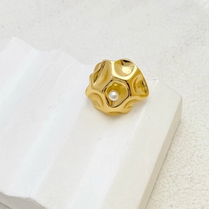 Detailed view of lava-textured gold ring featuring an elegant inlaid pearl detail
