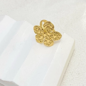 Detailed close-up of a large gold flower ring with hammered texture on white platform