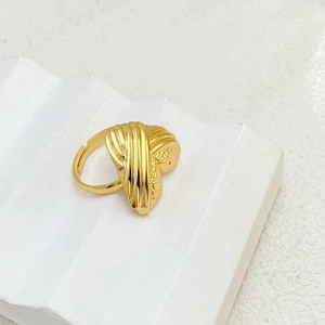 Close-up of golden adjustable ring with irregular wave texture on white stone stand