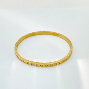 Dettaglio di un bracciale in acciaio inossidabile dorato con griglia quadra e cristalli
