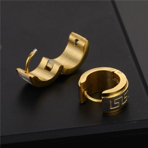 Macro detail of two-tone stainless steel hoop earrings featuring Greek Key pattern design