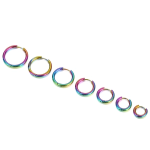 Seven pairs of rainbow plated stainless steel hoop earrings in varying sizes on white backdrop