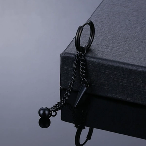 Close-up of matte black punk earrings with dangling chains and pointed spike charms