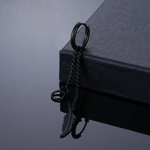 Macro detail of black stainless steel feather tassel earring on premium gift box edge
