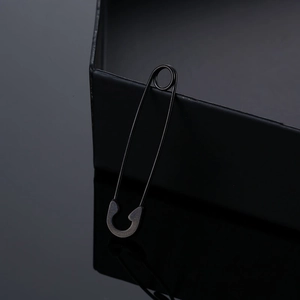 Macro shot of minimalist matte black stainless steel safety pin earrings with reflection