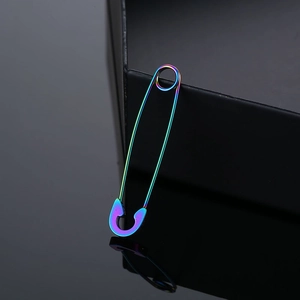 Rainbow gradient safety pin earring in polished stainless steel on a dark reflective surface