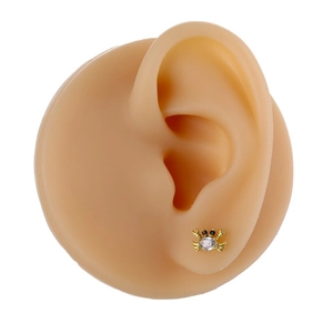 Detail view of a gold crab stud earring with white zircon inlay on a model ear