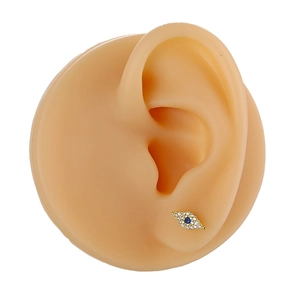 Close-up of golden Evil Eye stud earring with blue gemstone on silicone ear model