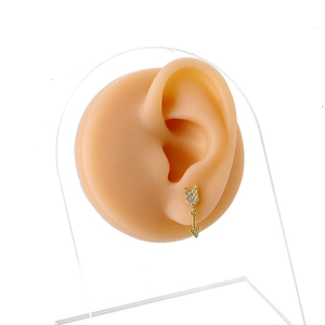Golden arrow drop earrings with cubic zirconia inlay shown on a silicone model ear