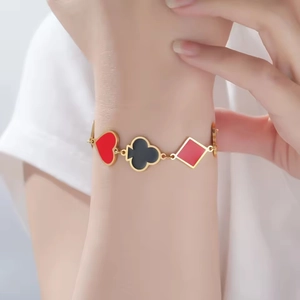Golden stainless steel bracelet featuring red and black poker suit charms on a wrist