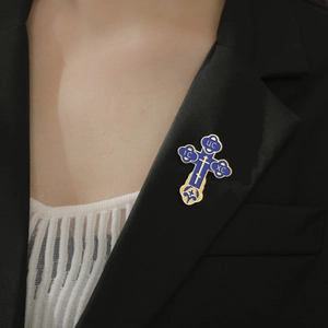 Blue and gold Orthodox cross brooch with IC XC letters on a black suit jacket lapel