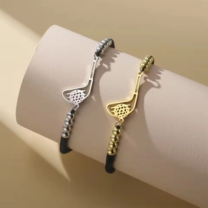 Detail von Golfschläger-Anhängern an schwarzen geflochtenen Armbändern in Gold und Silber