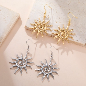 Detail view of spiral sun earrings in gold and silver finish on textured stone surface