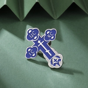 Detail of Orthodox cross enamel pin with blue finish on a textured green background