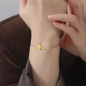 Detailansicht eines goldenen Golf-Armbands getragen über einem braunen Cordanzug