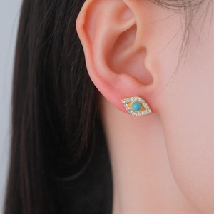304 stainless steel gold evil eye stud earrings with blue stone on a female model