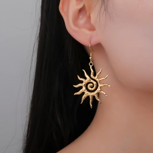 Golden stainless steel spiral sun drop earrings shown on a model for a stylish boho look
