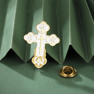 Macro shot of gold stainless steel Orthodox cross brooch with white enamel detail