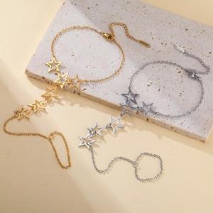 Detail of star charm finger bracelets in gold and silver finish with S.STEEL tags