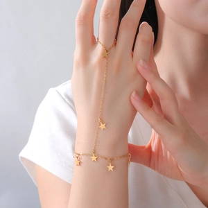 Detail of a gold stainless steel slave bracelet with star charms on a female model