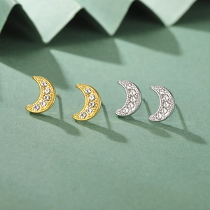 Dettaglio degli orecchini a luna in oro e argento con zirconi trasparenti