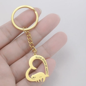 Golden sloth heart keychain with Slow Down Be Happy engraving in hand view