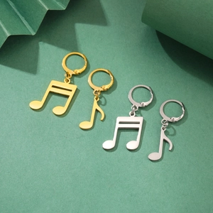 Detalle de pendientes con notas musicales en oro y plata con elegantes sombras suaves