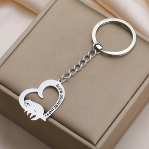 Detailed close-up of heart sloth keychain with 'Slow Down Be Happy' engraving