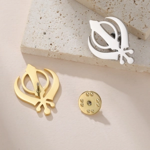 Macro detail of gold and silver Sikh Khanda pins showing front design and back clasp