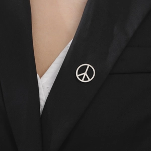 Silver peace sign brooch pin on black suit jacket for a stylish minimalist look