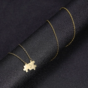 Dettaglio della collana con ciondolo a puzzle dorato su supporto per gioielli nero