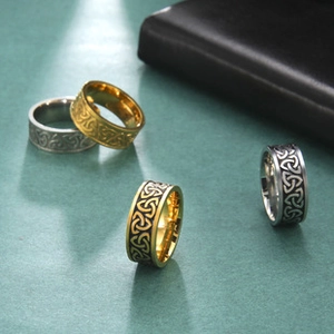Macro detail of stainless steel wide rings featuring intricate Celtic knot patterns in various finishes