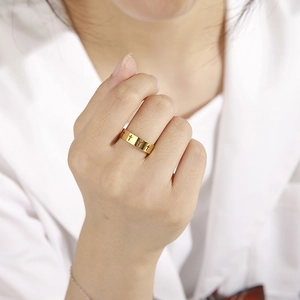 Poliertes Gold-Edelstahl-Ring mit hohlem Kreuz-Design an der Hand einer Person