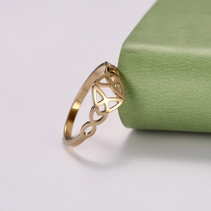 Macro side view of polished golden Celtic knot ring on a textured green background
