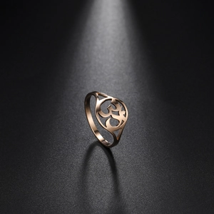 Elegant rose gold Om ring with intricate hollow engraving on a sleek black surface