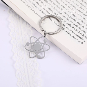 Makroaufnahme eines silbernen Atom-Schlüsselanhängers aus Edelstahl auf einem Buch