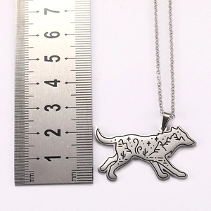 Detailed close-up of a wolf-shaped stainless steel pendant with desert mountain patterns