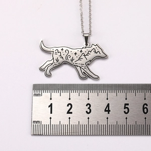 Detailed macro view of wolf-shaped stainless steel pendant showing engraved nature scenery