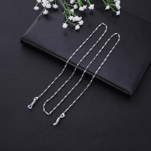 Silver beaded eyeglass chain with non-slip silicone loops on black leather surface