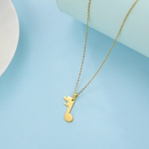 Macro detail of gold music note puzzle pendant necklace on a light blue background