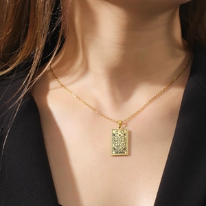 Detail of gold Gemini tarot card pendant necklace with celestial motifs on black suit