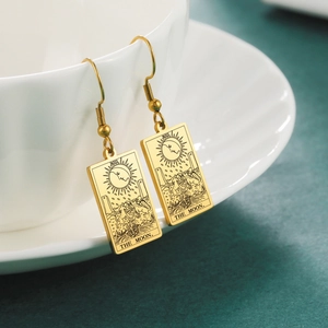 Detail of vintage gold tarot earrings featuring The Moon XVIII etching on a white cup