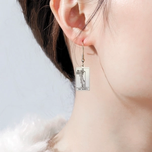 Close-up of The Hermit tarot card earrings in polished silver finish on a model