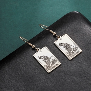 Detail of vintage tarot Strength card earrings with VIII roman numeral on black leather