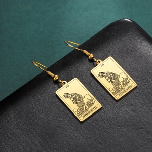 Macro shot of gold tarot strength earrings featuring detailed lion engraving on black leather