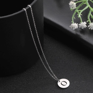 Detailed view of silver stainless steel necklace with round cutout letter O pendant