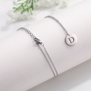 Detail of silver titanium steel necklace showing letter D pendant and lobster clasp link