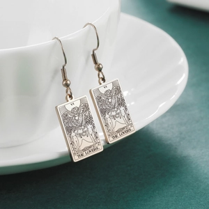 Vintage Tarot Lovers card drop earrings in stainless steel on a white ceramic cup