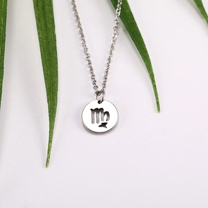 Detail of silver Virgo zodiac cutout pendant on stainless steel chain with green leaf decor